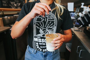 Barista at Mighty Missouri Coffee Shop holding iced coffee drink
